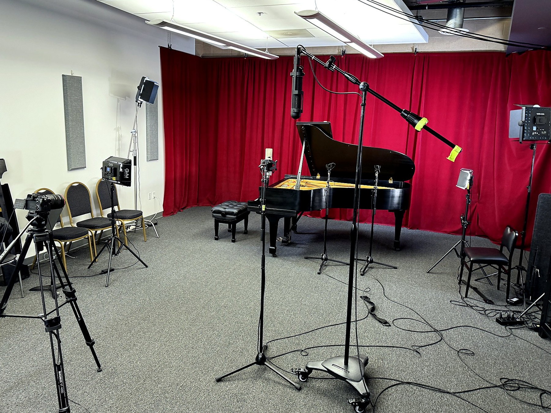 Mezo Records studio room with Steinway grand piano, red curtains, video lights, and microphone stands